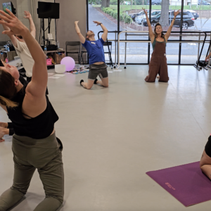 This image shows a group of dancers moving together in a circle as they warm up before class.