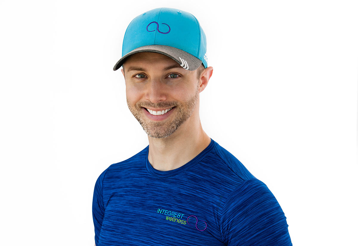 A portrait headshot of Jack Kirven wearing a blue shirt, aqua cap, and standing against a blank white background.