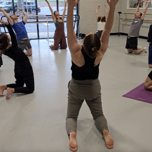 This image shows a group of dancers moving together in a circle as they warm up before class.